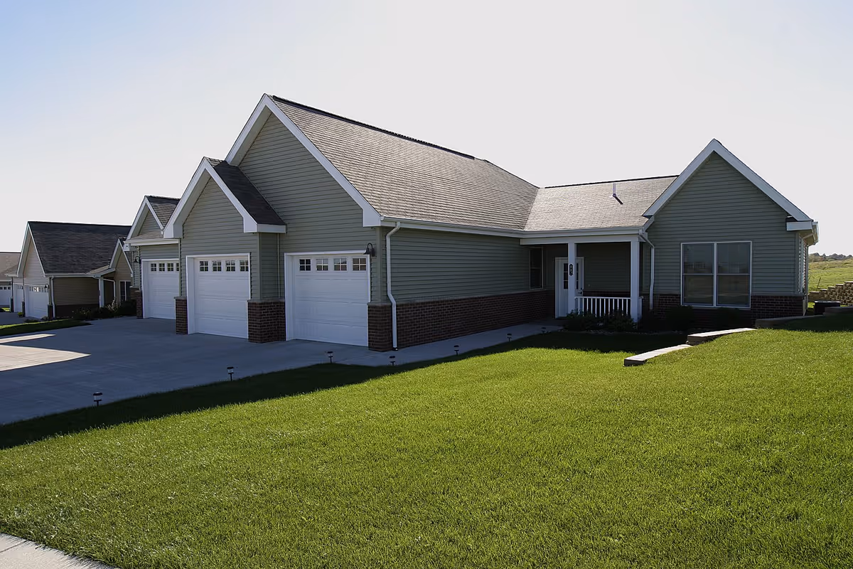 Single-story ranch-style building with three garage doors, a front porch, and a manicured lawn.