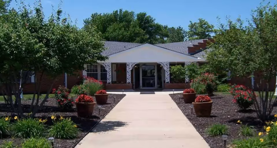 Front exterior of Avonlea Cottage of Quad Cities with walkway, trees, and planters.