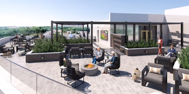 Rooftop patio with seating, planters, a pergola, and people gathered around a fire pit.