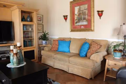 Cozy living room with beige sofa, colorful cushions, and a TV.