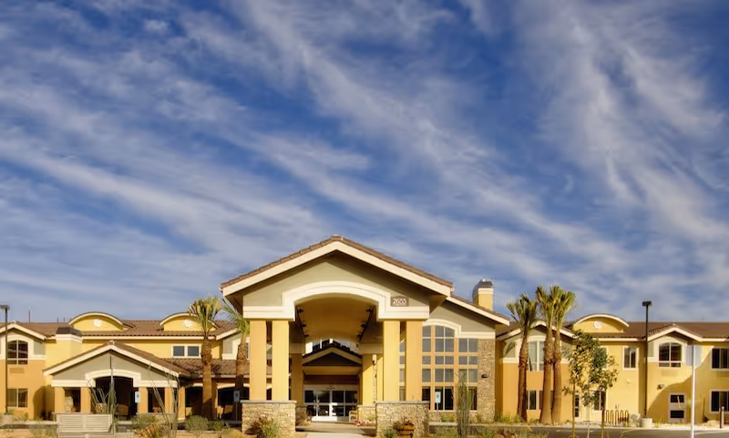 Front view of The Groves Assisted Living entrance with palm trees and a covered portico.