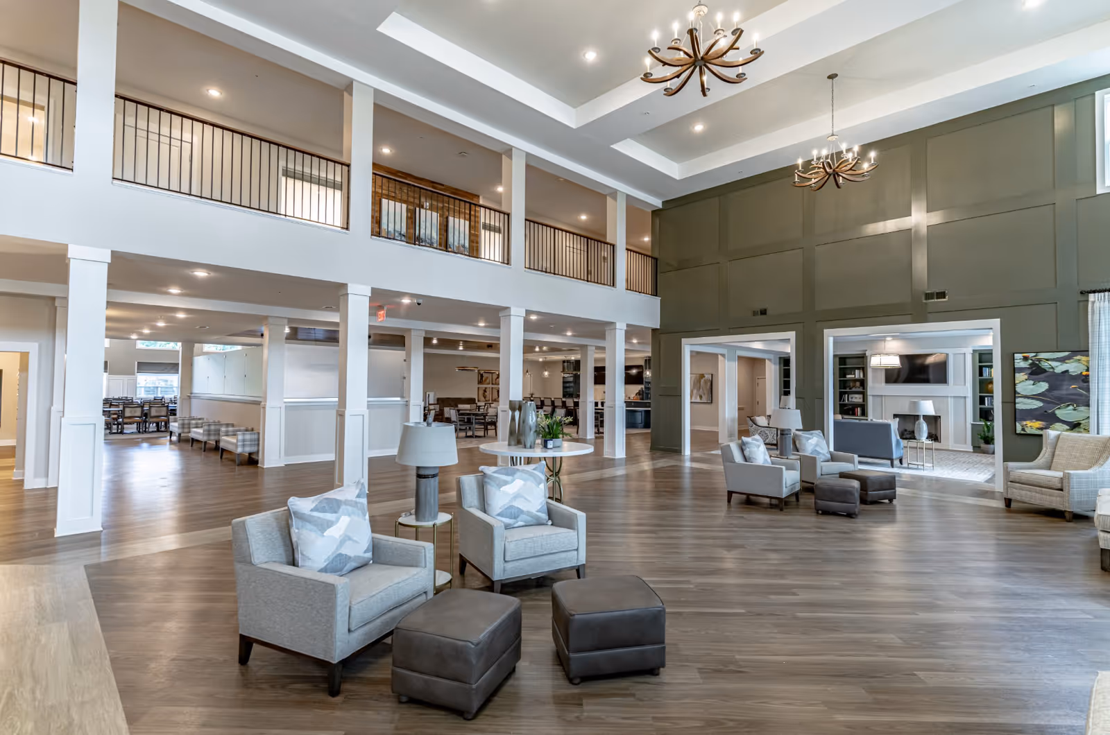 Spacious two-story senior living lobby with seating areas, chandeliers, and an open dining area.