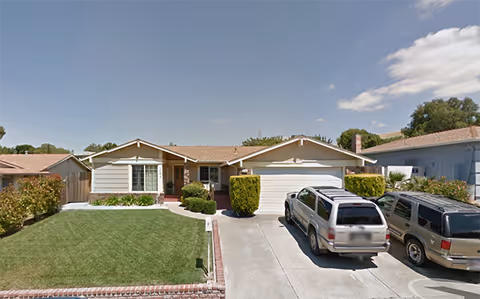 Single-story senior living facility front with two garages and parked cars.