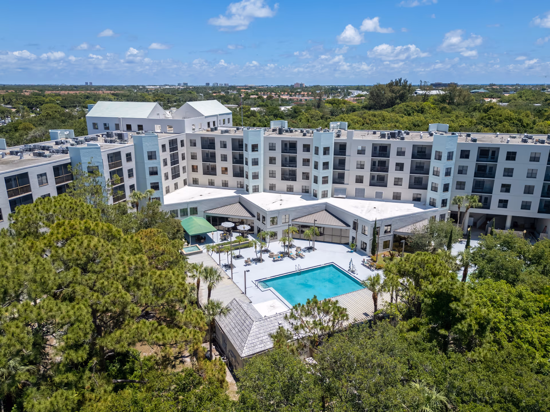 Aerial view of a multi-story senior living building surrounding a central courtyard with a swimming pool and lounge area.