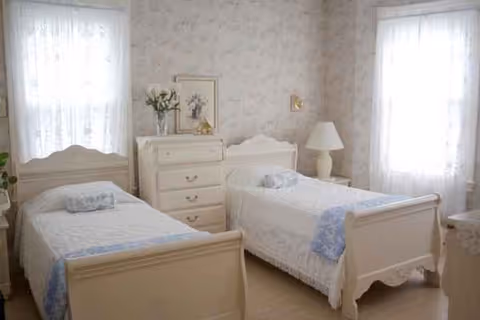 Two white twin beds flank a dresser in a bright, floral bedroom.