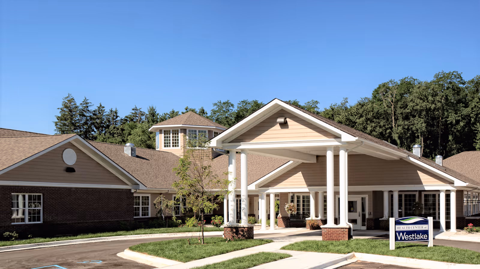 Front entrance of Westlake Health Campus featuring a covered porte-cochère with white columns, landscaping, and a sign.