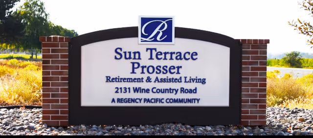 Outdoor sign for Sun Terrace Prosser Retirement & Assisted Living located at 2131 Wine Country Road, a Regency Pacific Community, surrounded by landscaping with rocks and plants.