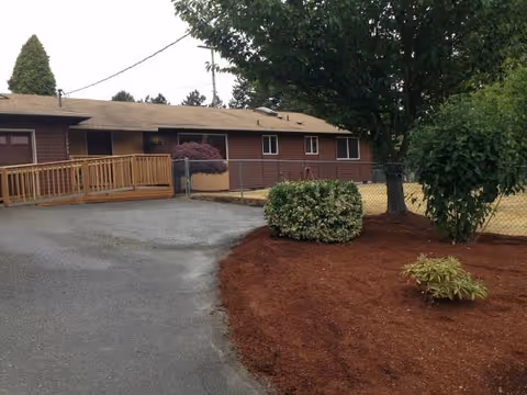 Exterior view of Evergreen Senior Care building with ramp, driveway, and landscaped area.