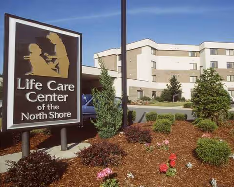 Sign for Life Care Center of the North Shore in front of a beige building.