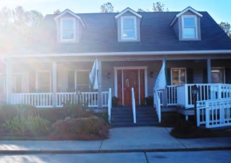 Front view of a senior living facility with a covered porch and red doors.