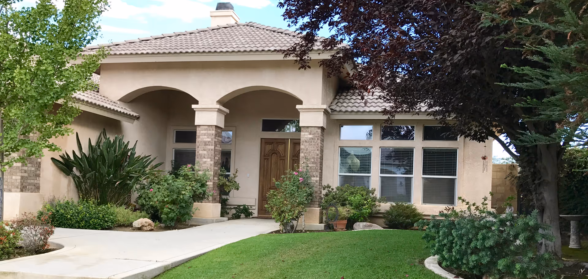 Front entrance of Village Gardens senior living facility with arches and well-kept landscaping.