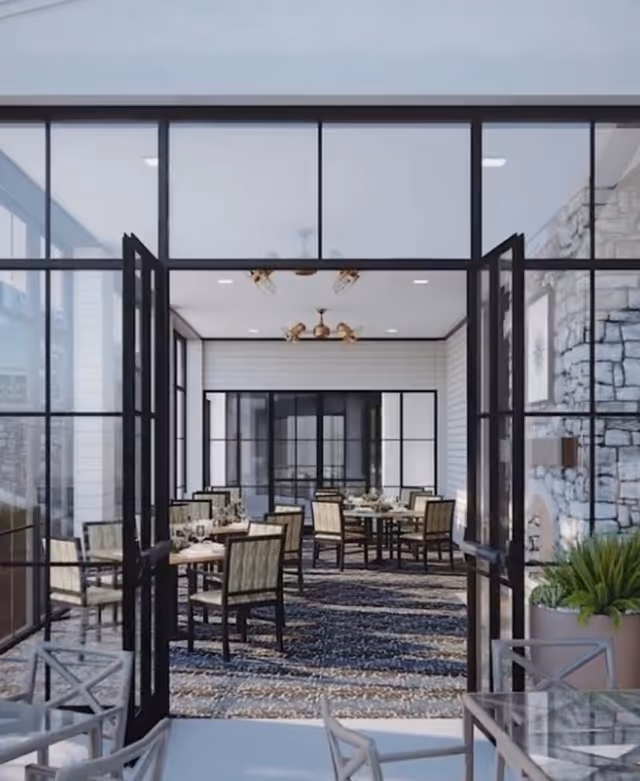 Glass-walled dining area seen through open black-framed doors with tables and chairs on a patterned rug.