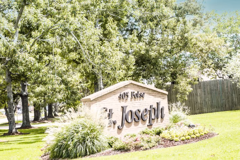 Brick landscaped entrance sign reading 'St. Joseph' surrounded by grass and trees.