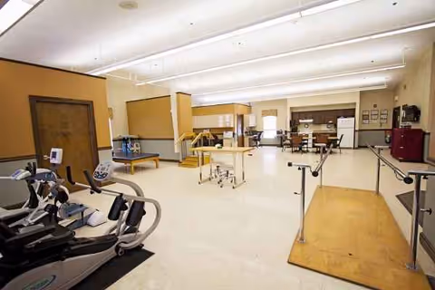 Spacious interior rehabilitation gym at Sprenger Health Care Heather Knoll, with bikes and parallel bars.