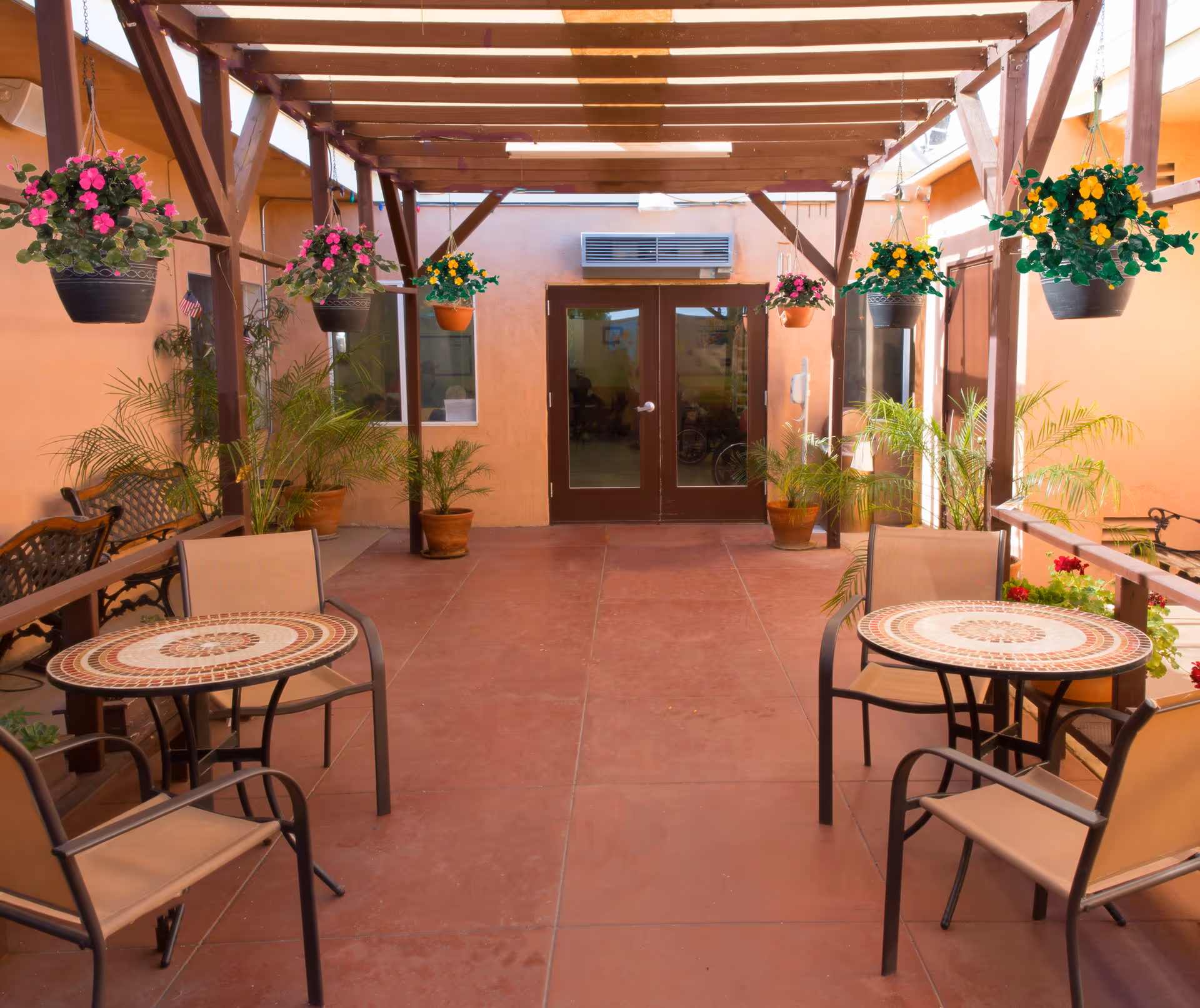 Outdoor patio area with hanging plants and tables.
