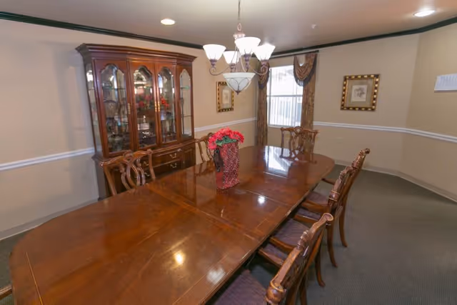Formal dining room with a long polished wooden table, matching chairs, a china cabinet and a chandelier.