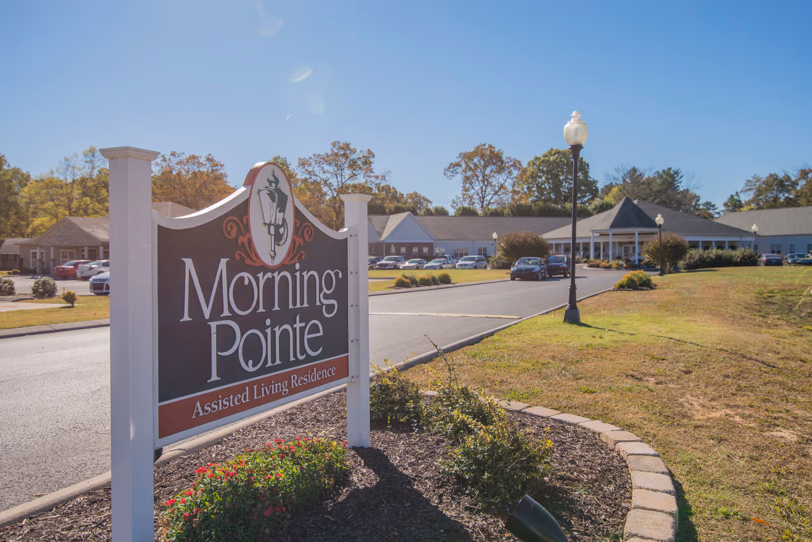 Entrance sign for Morning Pointe assisted living residence with the facility building and driveway in the background.