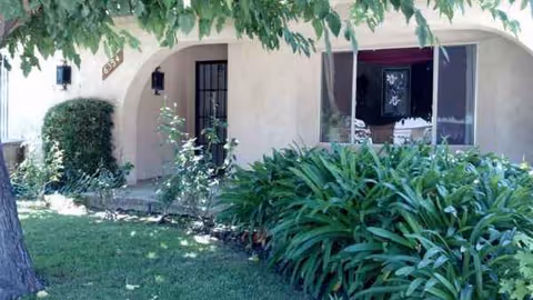 Exterior view of Genesis Manor with arched entry, lush greenery, and manicured lawn.