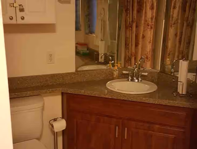Bathroom vanity with sink, mirror, and toilet in a senior living facility.