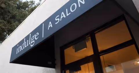 Exterior view of a building entrance featuring the indulge A Salon sign.