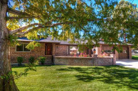 Brick exterior of a senior living facility with a tree, lawn, and porch seating.