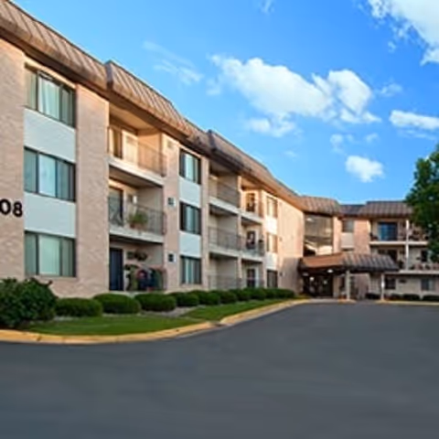 Exterior view of Woodbury Villa senior living facility, showing a multi-story building with balconies.