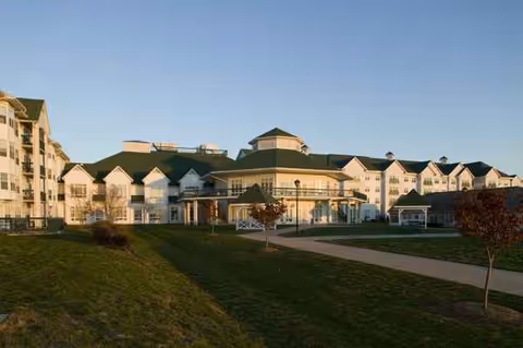 Exterior view of Asbury Solomons Waterfront Senior Living campus with green lawn and walkway.