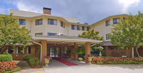 Front entrance of Regency House by Barclay House with covered drop-off and manicured landscaping.