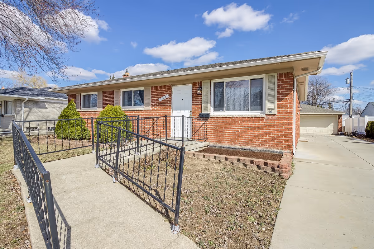 Brick Stratford House exterior with a ramp, walkway, and driveway to a garage.
