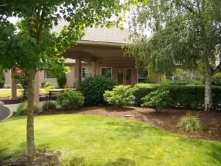 Front view of a senior living facility with a covered entrance and landscaped lawn.