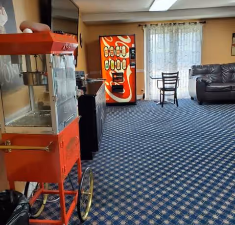 Indoor lounge area with a red popcorn cart, Coca-Cola vending machine, and seating.