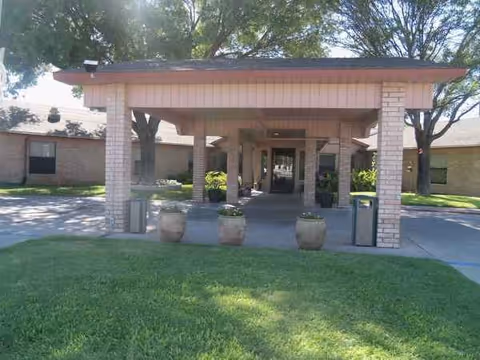 Covered entrance with brick columns and a walkway into the nursing facility.