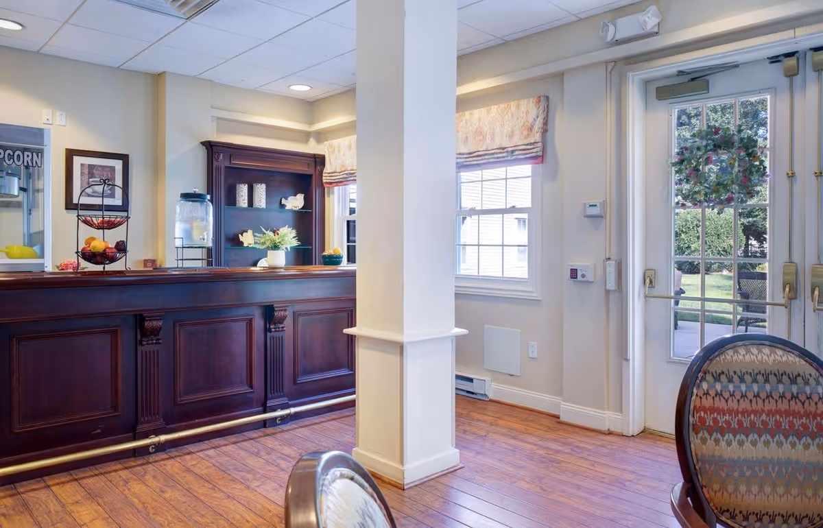 Reception/common area with a dark wood front desk, shelving, chairs, and glass doors with a wreath leading outside.