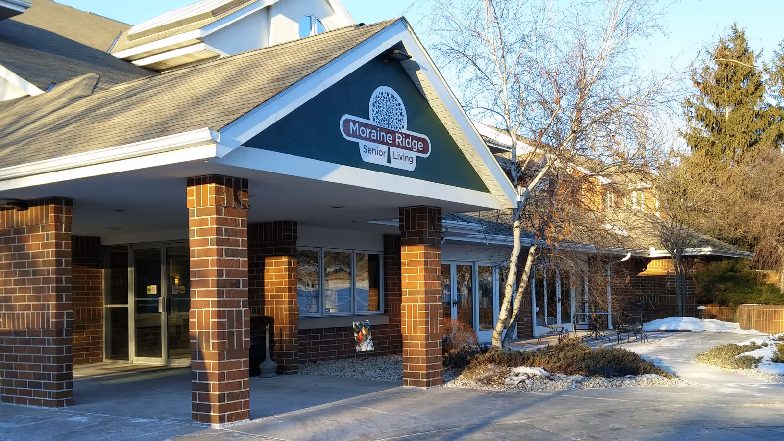 Front entrance of Moraine Ridge Senior Living with a covered drive, brick columns, and the facility sign above the entry.