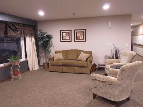 Cozy living room in Autumn Hills with sofa, armchairs, plants, and framed art.