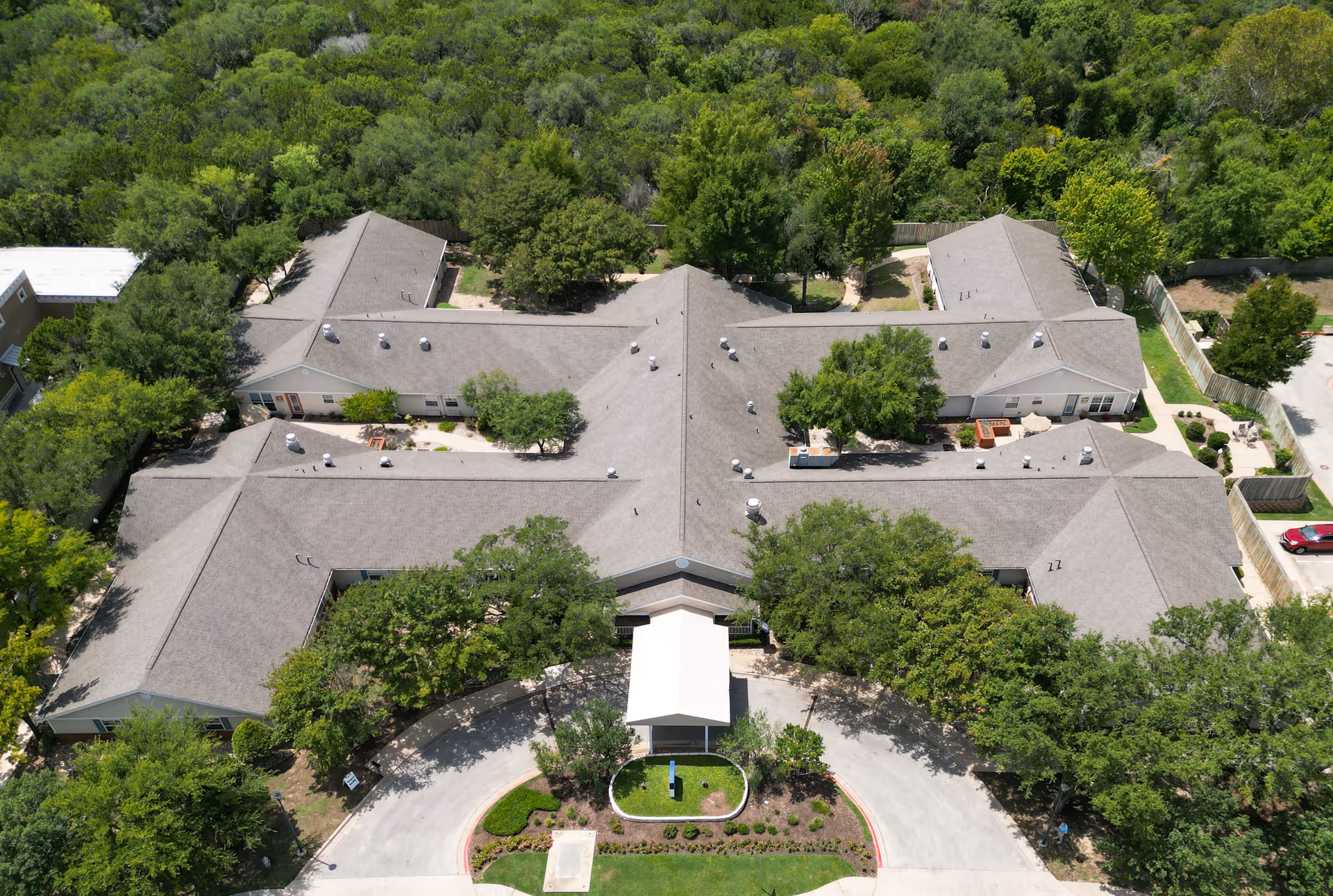 Aerial view of a single-story memory care facility surrounded by trees with a circular drive at the entrance.