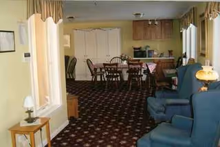 Interior of Elizabeth Calsey House common room with teal chairs and dining table.