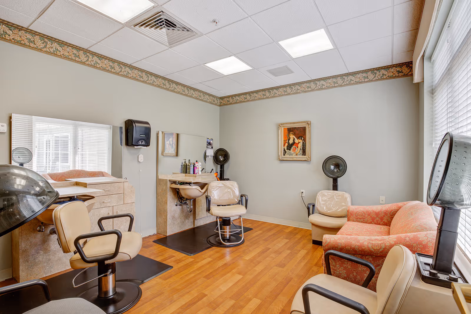 Interior salon room with styling chairs, hooded hair dryers, mirrors, and a small seating area.