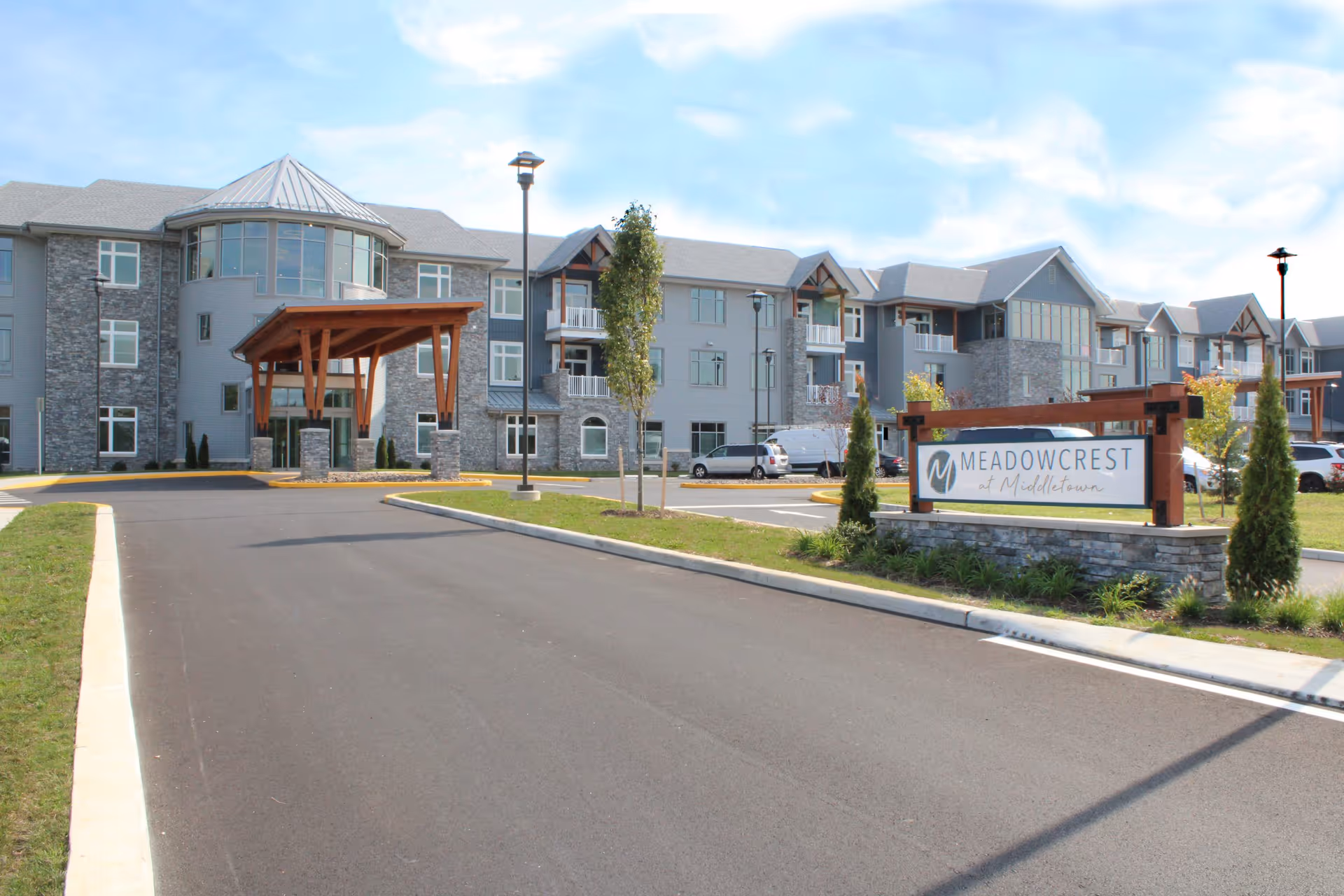 Front exterior of the Meadowcrest at Middletown senior living building showing the driveway, covered entrance, and signage.