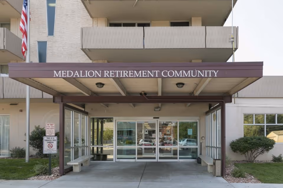Front entrance of Medallion Retirement Community showing a covered canopy with the facility name above sliding glass doors.