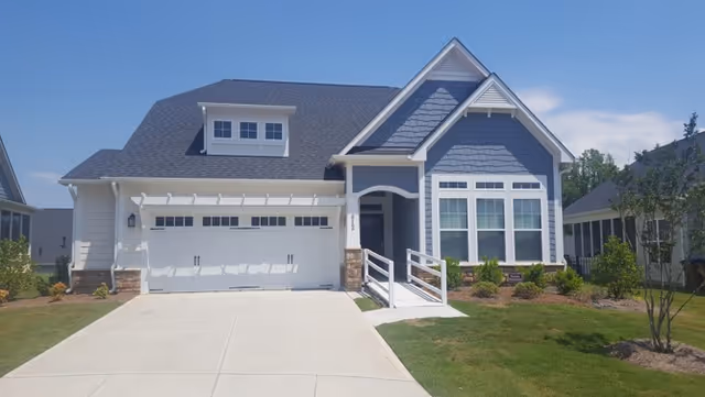 Blue and white house with a two-car garage and landscaped front yard.