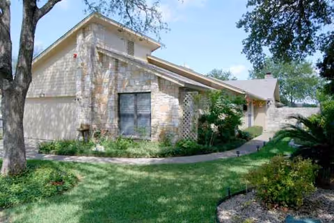 A single-story building with stone and siding, a manicured lawn, and trees.