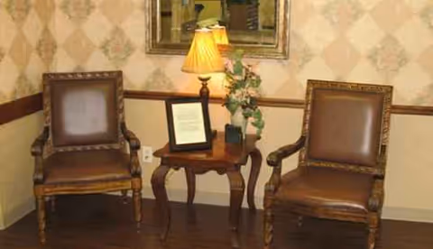 Two brown leather chairs sit beside a wooden table with a lamp.