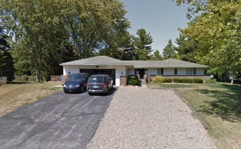 Front exterior of Litchfield senior living facility with two cars and gravel driveway.
