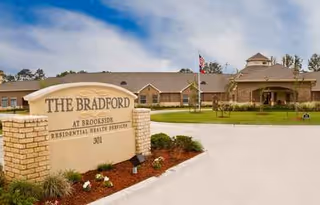 Exterior view of The Bradford at Brookside senior living facility with sign and flag.