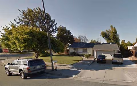 Front exterior of a single-story care home with a driveway and parked cars