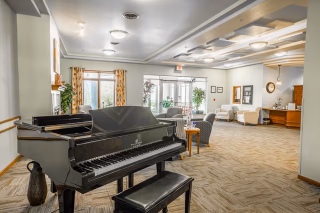 Lobby of Coventry Village showing a black grand piano, seating areas, and a reception desk.