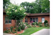 Exterior brick Mayflower Community building with manicured landscaping and trees.