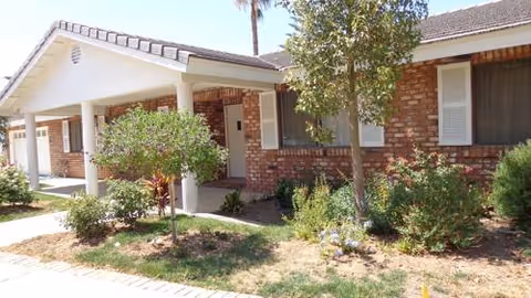 Exterior view of a brick senior living facility with a covered entrance and landscaping.