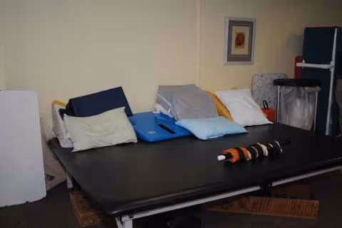 Therapy bed with pillows in a small interior rehab room.